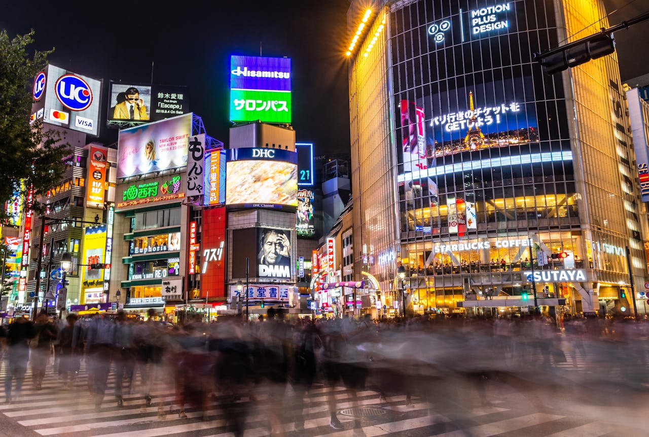 A bustling night scene at Shibuya Crossing in Tokyo, showcasing illuminated billboards and crowds.